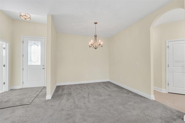 carpeted entrance foyer with an inviting chandelier