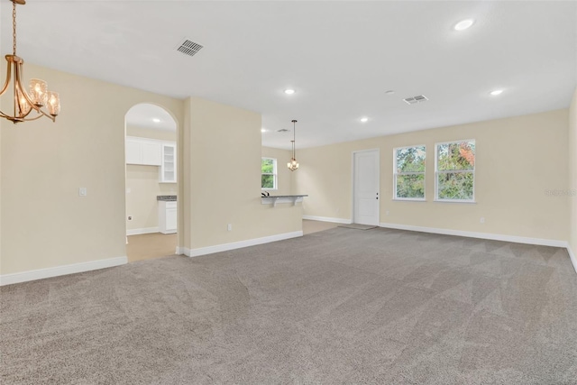 unfurnished living room featuring a chandelier and carpet