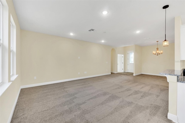 unfurnished living room with light carpet and an inviting chandelier