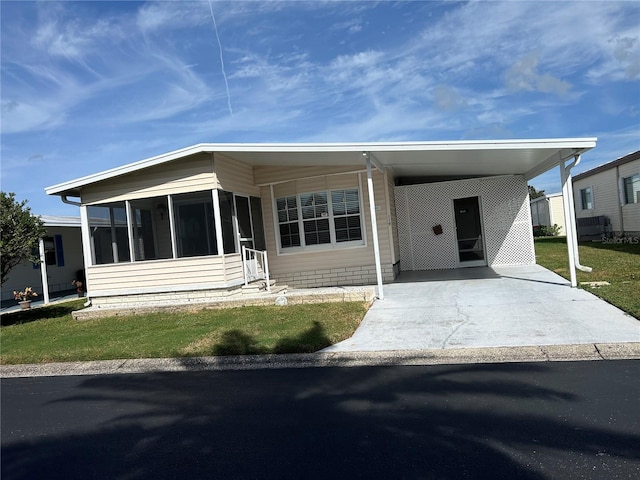 manufactured / mobile home with a front yard, a sunroom, and a carport