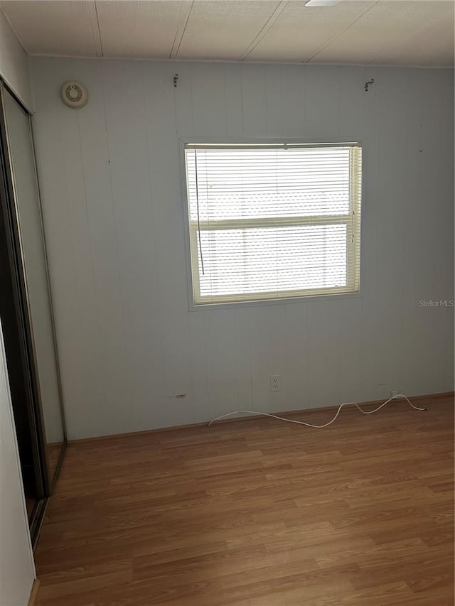 unfurnished room with hardwood / wood-style floors and wooden walls