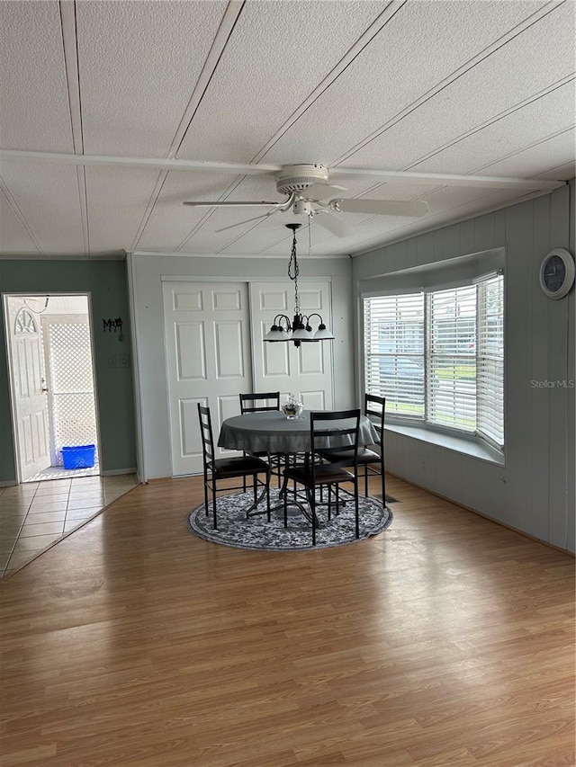 dining area featuring wood-type flooring, a textured ceiling, and ceiling fan with notable chandelier