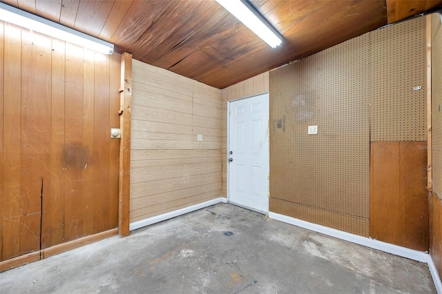 interior space with lofted ceiling, wooden ceiling, wooden walls, and concrete flooring