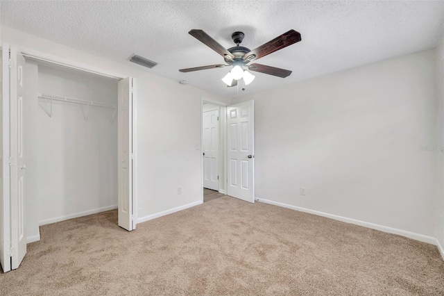 unfurnished bedroom featuring a textured ceiling, ceiling fan, light carpet, and a closet