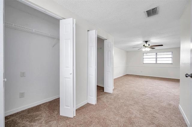 unfurnished bedroom featuring light carpet, a textured ceiling, and ceiling fan