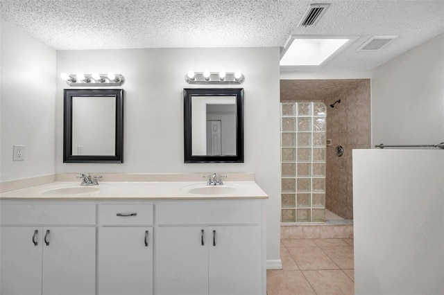 bathroom with a tile shower, a textured ceiling, and tile patterned floors