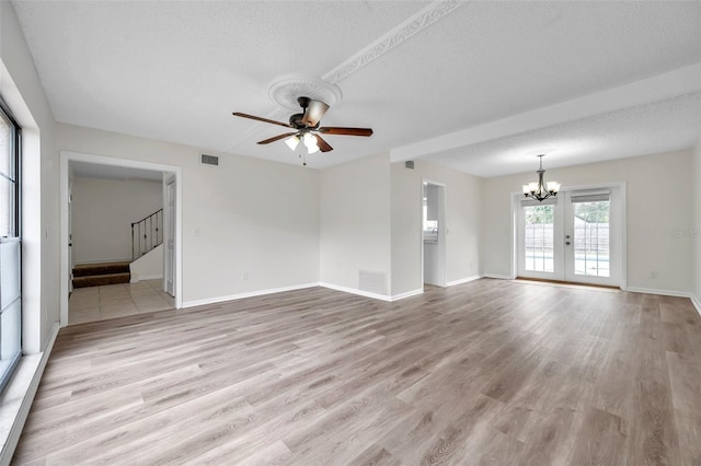 unfurnished living room featuring light wood-type flooring, french doors, ceiling fan with notable chandelier, and a textured ceiling