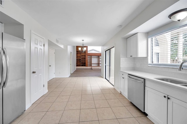 kitchen featuring white cabinetry, sink, stainless steel appliances, decorative light fixtures, and decorative backsplash