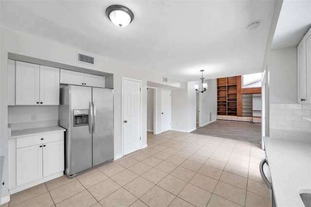 kitchen with pendant lighting, an inviting chandelier, white cabinets, stainless steel refrigerator with ice dispenser, and decorative backsplash