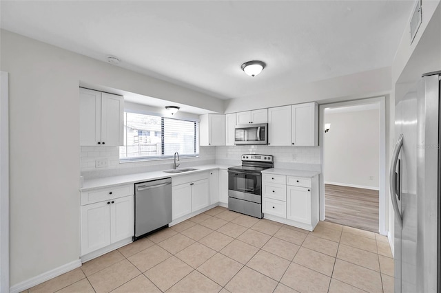 kitchen with white cabinets, backsplash, stainless steel appliances, and sink