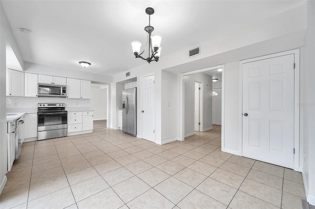 kitchen with stainless steel appliances, light tile patterned floors, decorative light fixtures, a chandelier, and white cabinetry