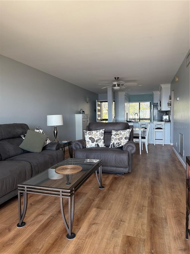 living room featuring light wood-type flooring, ceiling fan, and sink