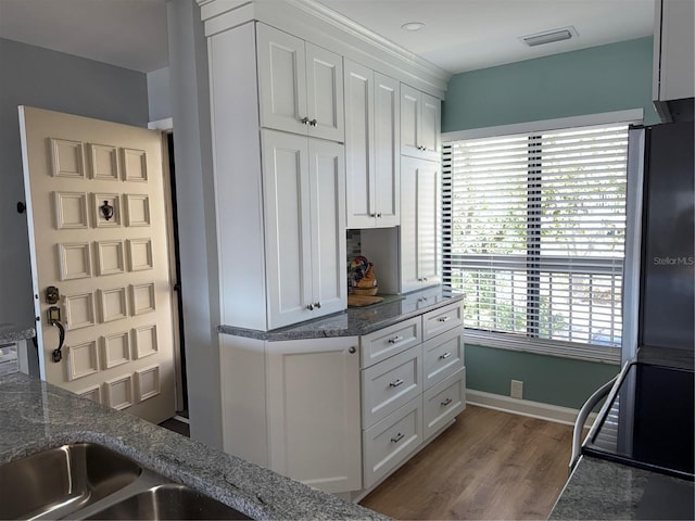 kitchen with white cabinets, dark hardwood / wood-style floors, and dark stone countertops