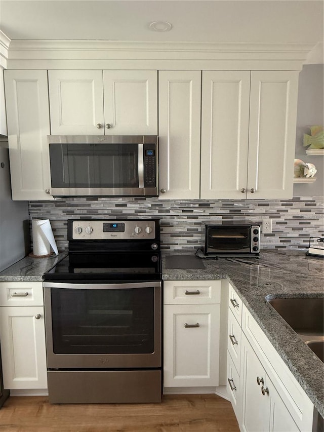 kitchen with white cabinets, stainless steel appliances, backsplash, and light hardwood / wood-style flooring