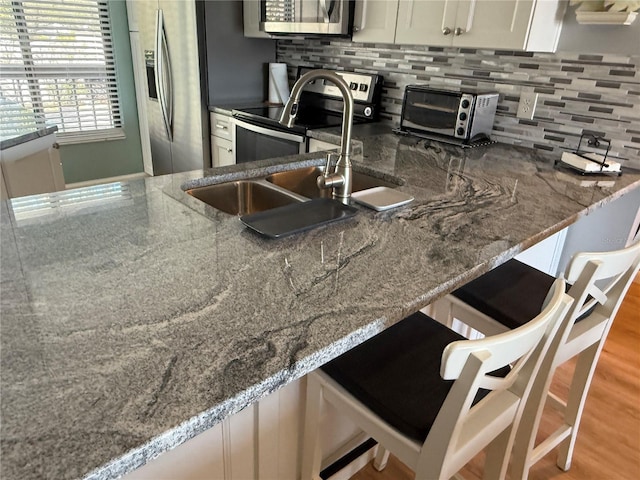 6268 Palma Del Mar Blvd S Unit 215, Saint Petersburg, FL 33715 - kitchen with appliances with stainless steel finishes, white cabinetry, stone countertops, decorative backsplash, and a sink