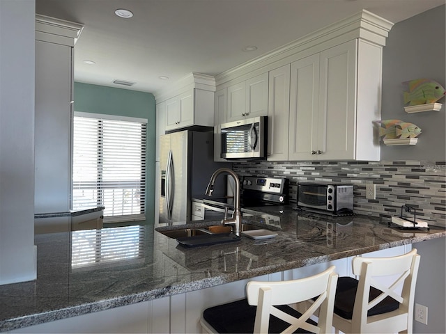 6268 Palma Del Mar Blvd S Unit 215, Saint Petersburg, FL 33715 - kitchen with stainless steel appliances, tasteful backsplash, a peninsula, dark stone counters, and white cabinetry