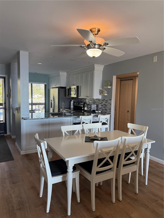 dining area featuring dark hardwood / wood-style flooring, ceiling fan, and sink