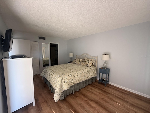 bedroom with a textured ceiling and dark hardwood / wood-style floors