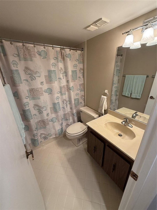 bathroom with toilet, vanity, and tile patterned floors