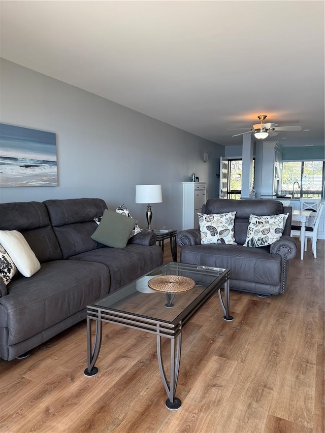 living room featuring light hardwood / wood-style flooring, ceiling fan, and sink