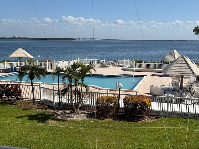 view of pool featuring a water view, a yard, and a patio area