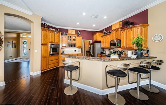 kitchen featuring a breakfast bar, dark hardwood / wood-style flooring, kitchen peninsula, and appliances with stainless steel finishes