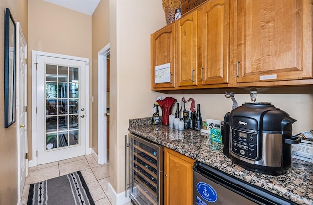 bar featuring dishwasher, light tile patterned floors, beverage cooler, and dark stone countertops