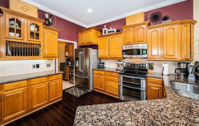 kitchen featuring appliances with stainless steel finishes, dark hardwood / wood-style floors, dark stone countertops, and sink