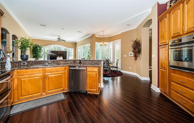 kitchen featuring ceiling fan with notable chandelier, ornamental molding, dark wood-type flooring, and appliances with stainless steel finishes