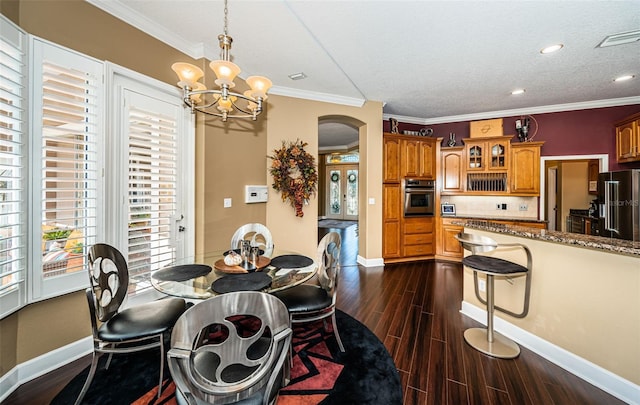 dining space featuring dark hardwood / wood-style flooring, ornamental molding, a textured ceiling, and a chandelier