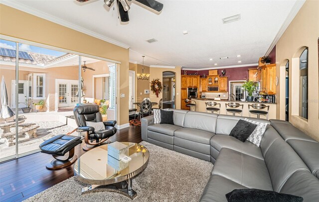 living room featuring crown molding, ceiling fan with notable chandelier, and hardwood / wood-style flooring