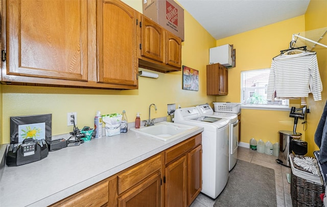 laundry area with cabinets, light tile patterned floors, washing machine and dryer, and sink