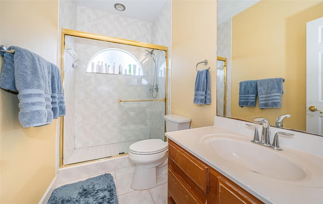 bathroom featuring tile patterned flooring, vanity, toilet, and a shower with door