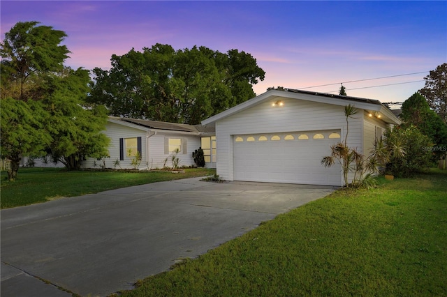 ranch-style home with a garage and a yard