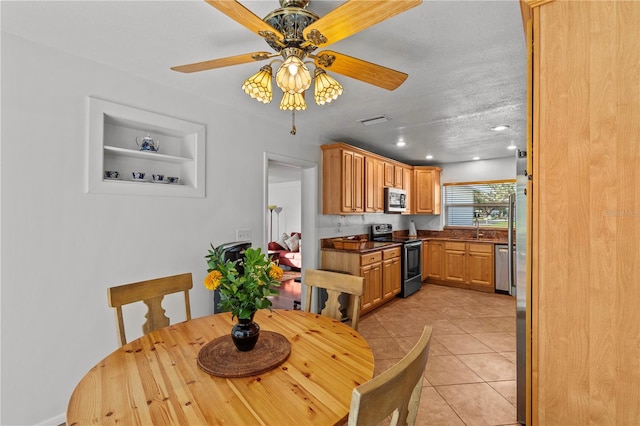 tiled dining area featuring ceiling fan, a textured ceiling, and sink