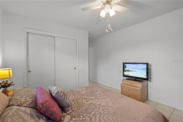 bedroom featuring light tile patterned flooring, a textured ceiling, ceiling fan, and a closet