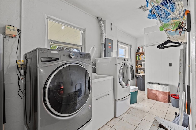 laundry room with electric panel, washing machine and dryer, cabinets, and light tile patterned floors