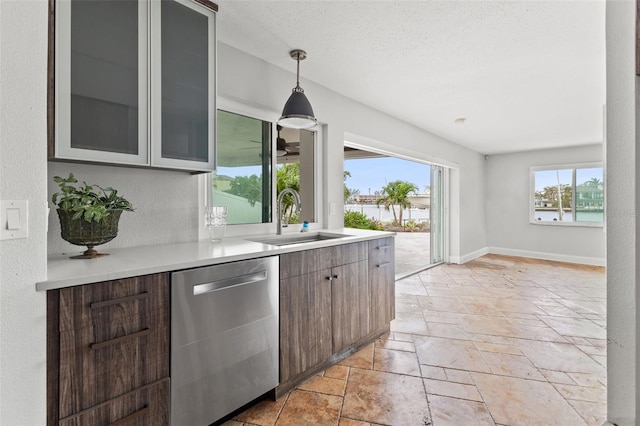 kitchen featuring a textured ceiling, dishwasher, sink, and decorative light fixtures