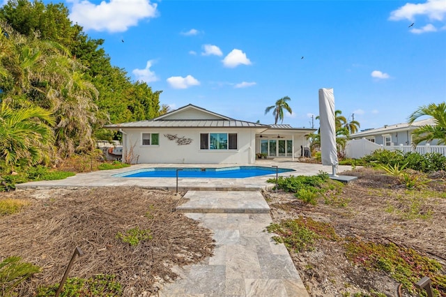 back of property with ceiling fan, a patio area, and a fenced in pool