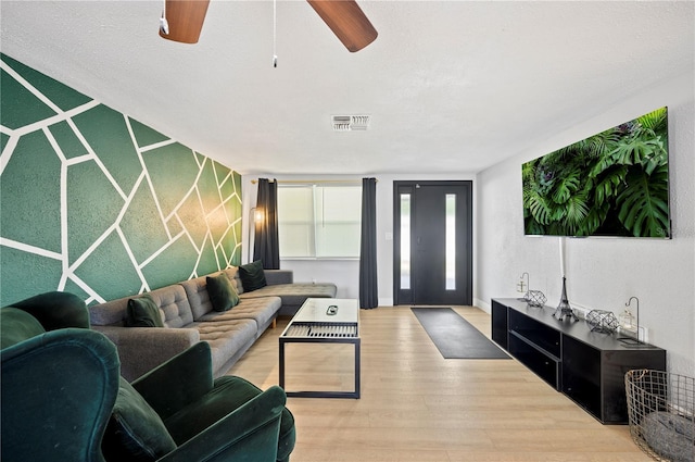 living room with light wood-type flooring, a textured ceiling, and ceiling fan