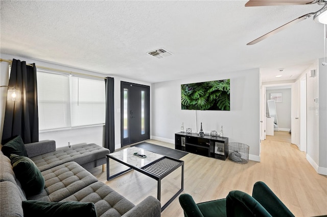 living room with a textured ceiling, ceiling fan, and light hardwood / wood-style flooring