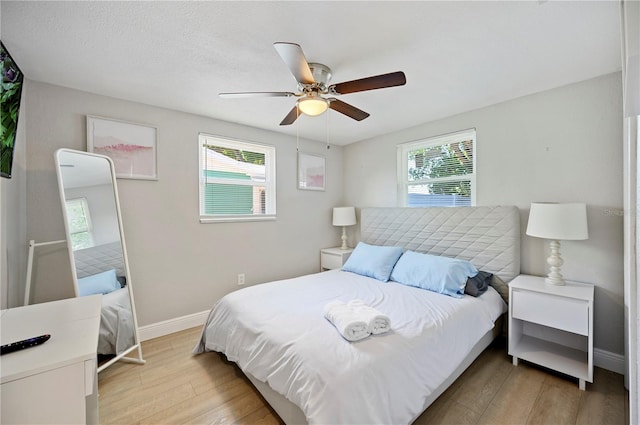 bedroom featuring light wood-type flooring, multiple windows, and ceiling fan