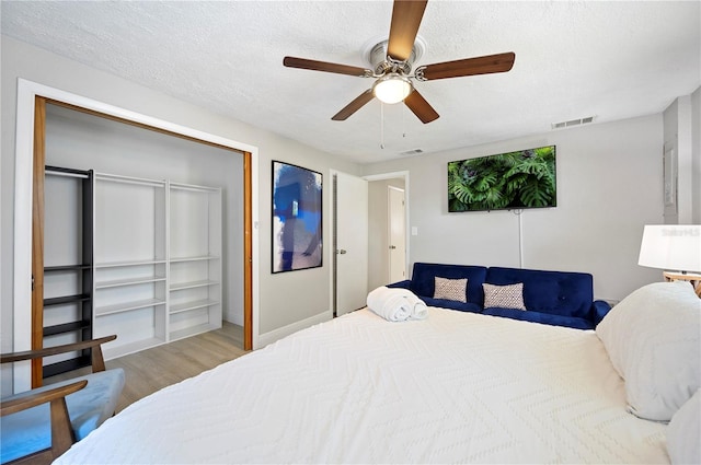 bedroom with hardwood / wood-style flooring, ceiling fan, a textured ceiling, and a closet