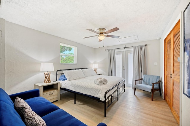 bedroom with a textured ceiling, light wood-type flooring, ceiling fan, and a closet