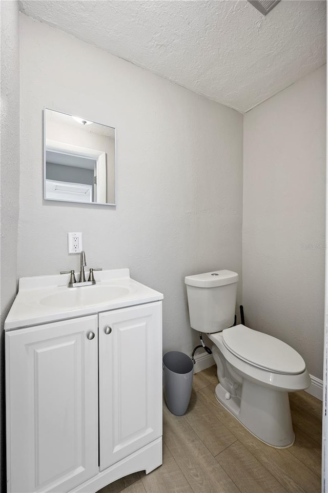 bathroom with toilet, vanity, hardwood / wood-style floors, and a textured ceiling