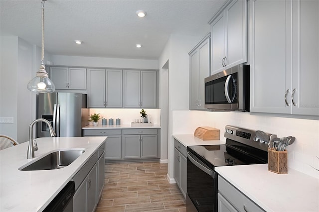 kitchen featuring stainless steel appliances, decorative backsplash, hanging light fixtures, sink, and light wood-type flooring