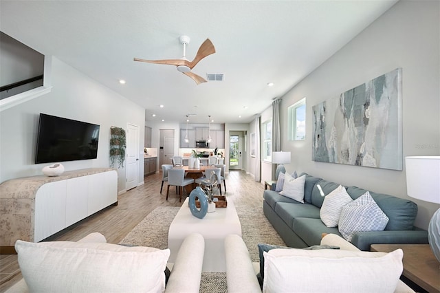 living room with ceiling fan and light hardwood / wood-style flooring