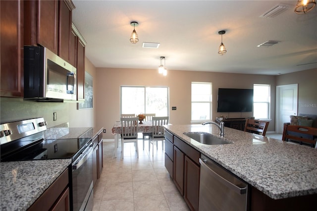 kitchen with appliances with stainless steel finishes, sink, plenty of natural light, and a kitchen island with sink