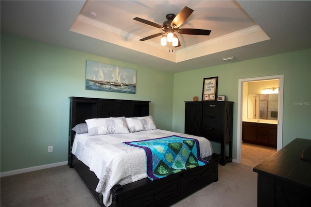 carpeted bedroom featuring ceiling fan, a raised ceiling, crown molding, and ensuite bath