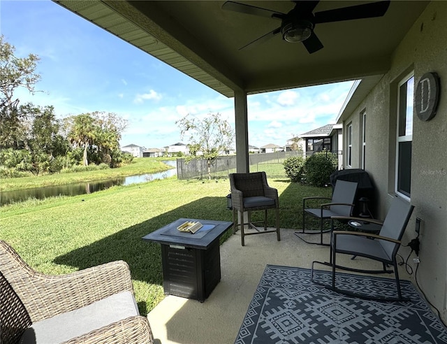 view of patio / terrace featuring ceiling fan, a water view, and a fire pit